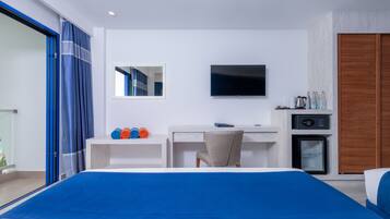 A hotel room with a bed, a desk, a television, and a minibar.