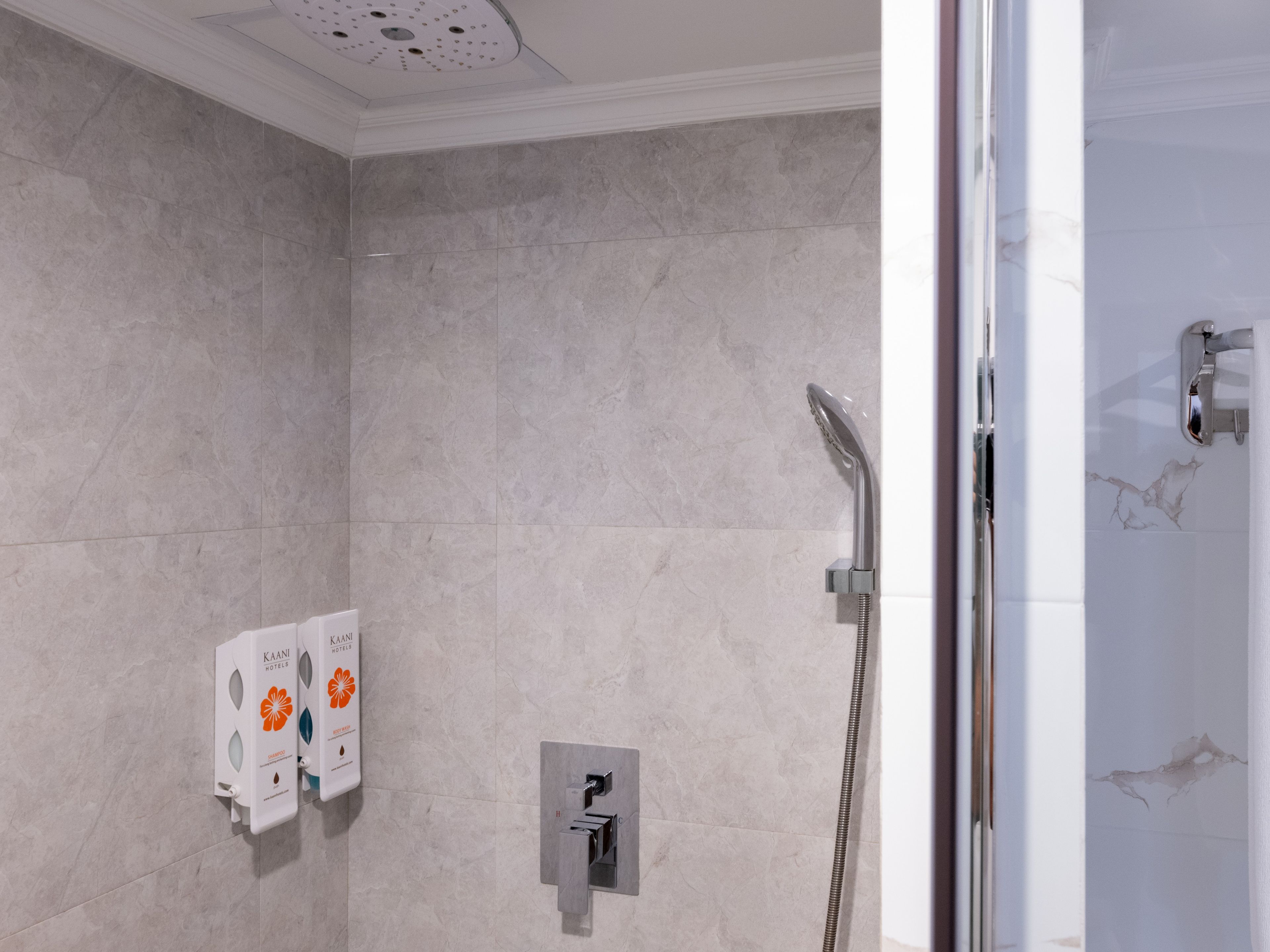 Une salle de bain équipée d’une douche, d’un distributeur de serviettes et d’un sèche-mains.