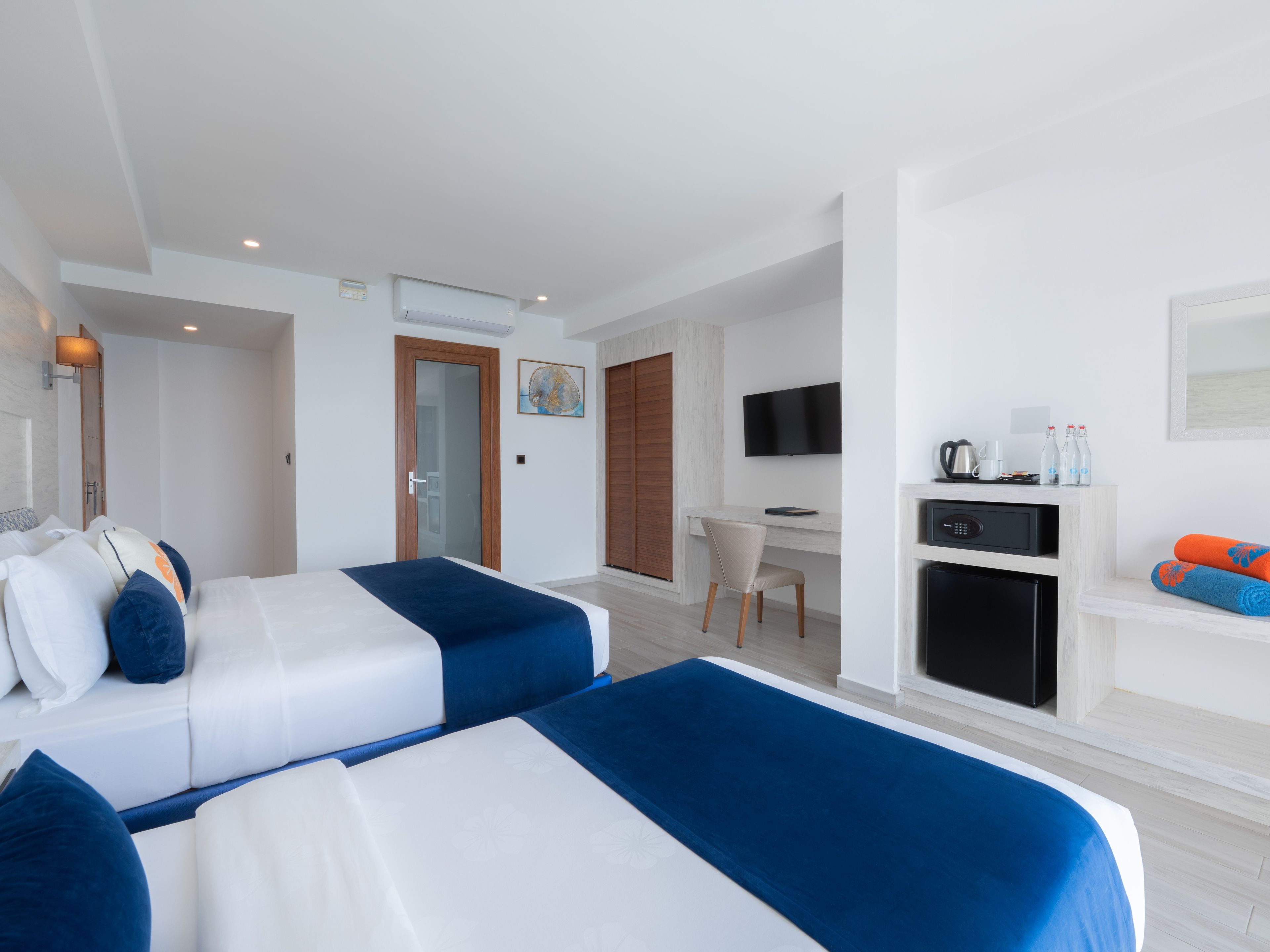 Una habitación de hotel con dos camas, un escritorio, un televisor y un minibar.