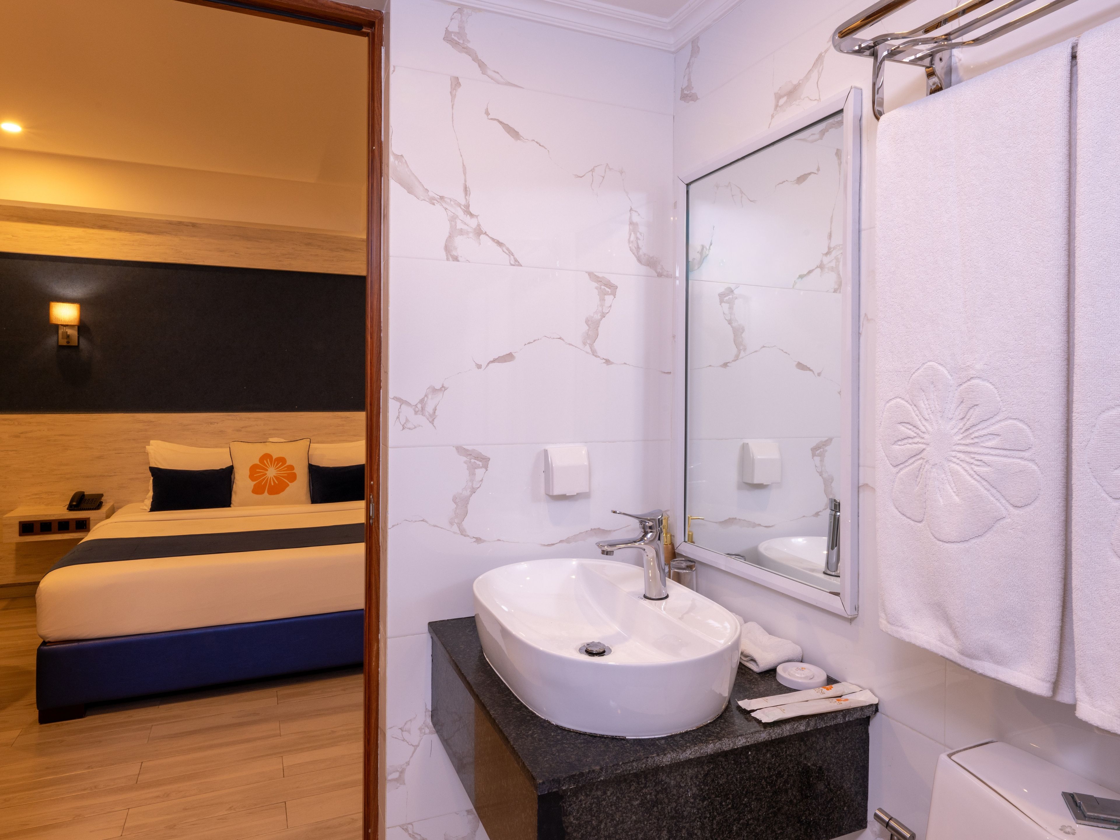 A hotel room with a bed, a bathroom with a sink, and a mirror.
