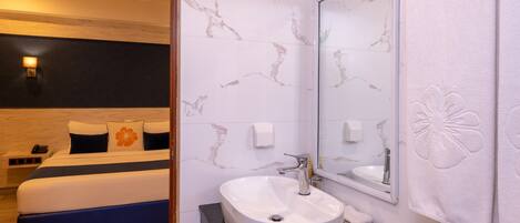 A hotel room with a bed, a bathroom with a sink, and a mirror.