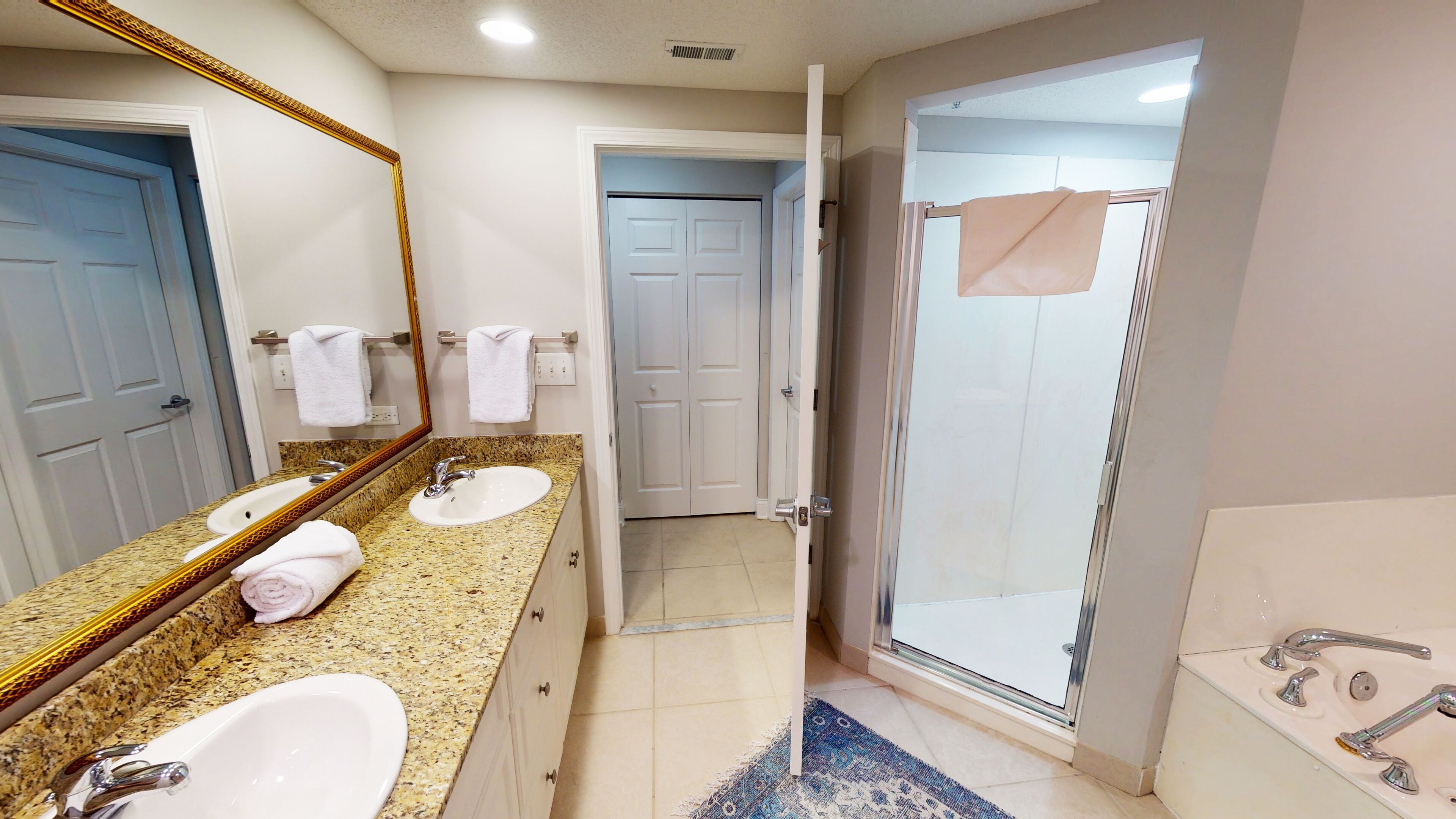 A bathroom with two sinks, a large mirror, and a shower area.