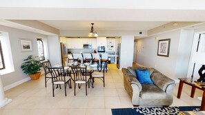 A spacious living area with a dining table, chairs, a sofa, and a kitchen in the background. - Beachfront Joy | Poolside Fun | Oceanfront Views | OB 203 (Myrtle Beach)