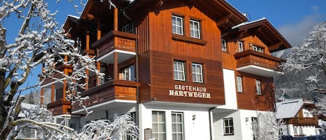 A multi-story wooden building with balconies and a sign reading 'Gastehaus Hartweger.'