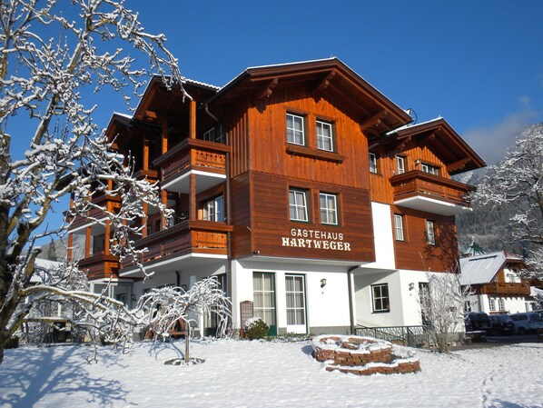 A multi-story wooden building with balconies and a sign reading 'Gastehaus Hartweger.'