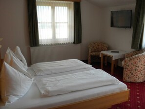 A hotel room with a double bed, a small table, a chair, and a television. - Apartment Kufstein, Luser - guest house Hartweger (Weißenbach)