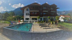 A hotel with a swimming pool, outdoor seating, and mountain views. - Apartment Kufstein, Luser - guest house Hartweger (Weißenbach)