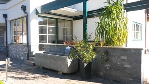 A building with a covered outdoor seating area, stone steps, and potted plants. - Apartment Kufstein, Luser - guest house Hartweger (Weißenbach)