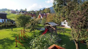 A playground with a slide, swings, and a climbing structure in a grassy area with houses in the background. - Apartment Kufstein, Luser - guest house Hartweger (Weißenbach)