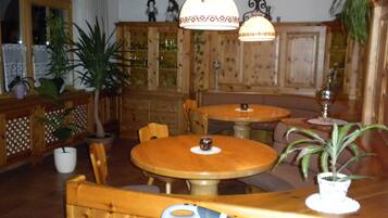 Ein Holzinterieur mit runden Tischen und Stühlen, Blumentöpfen und einer dekorativen Deckenleuchte.