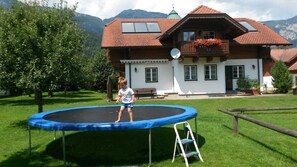 A house with a large front yard, a trampoline, and a wooden fence. - Apartment Stoder - guest house Hartweger (Weißenbach)