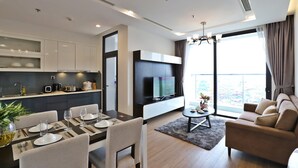 A modern living room with a dining area, a kitchen, and a large window with a city view.