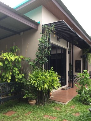 A house with a covered porch, potted plants, and a small garden area. - Barbe La Maison (Hua Hin)