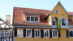 A yellow building with multiple windows and shutters, a balcony, and potted plants on the ground floor. - In the middle of Tübingen's old town - and live quietly on a sunny 65 sqm! (Tübingen)