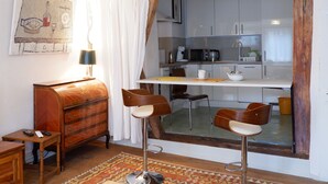 A compact living space with a kitchenette, a wooden cabinet, a dining area with stools, and a patterned rug. - In the middle of Tübingen's old town - and live quietly on a sunny 65 sqm! (Tübingen)