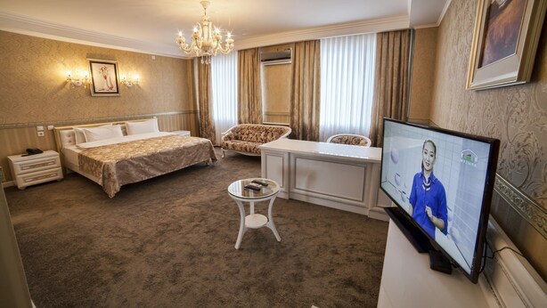 A hotel room with a bed, a desk, a television, and a small table. - Hotel Orto-Asia (Osh)