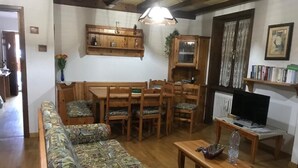 Ein gemütliches Wohnzimmer mit einer Couch, einem Holzesstisch und Stühlen.
