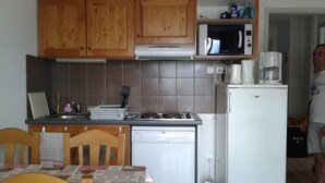 Una cocina compacta con armarios de madera, microondas, cafetera y refrigerador.