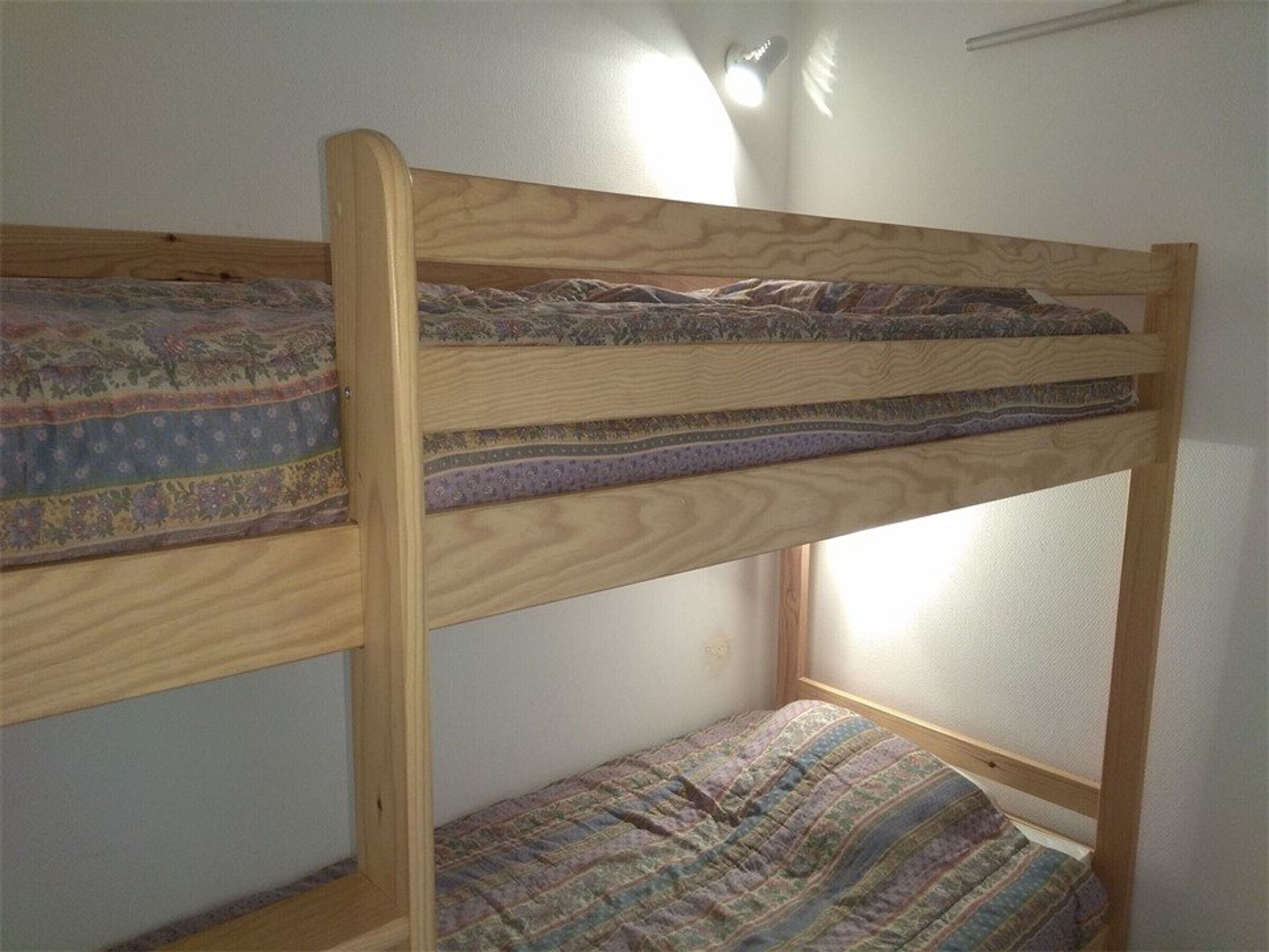Un letto a castello con una coperta a motivi e una finestra sopra.