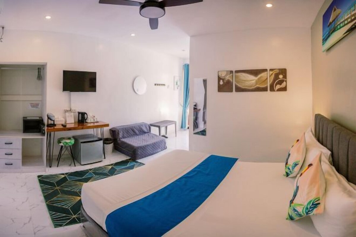 A modern hotel room with a bed, desk, and seating area.