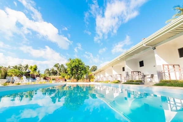A swimming pool with lounge chairs and a building with a flat roof.