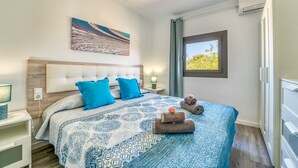 Une chambre à coucher avec un grand lit, une tête de lit, une table de chevet, une fenêtre donnant sur un beau paysage et un tableau accroché au mur.