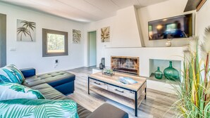 Un salon moderne avec une cheminée, un canapé, une table basse et des œuvres d’art murales.