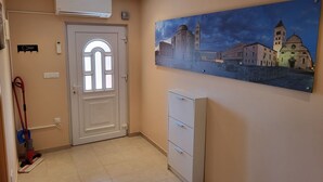 Un passadís amb una porta blanca, un aparell de climatització, un quadre d'un paisatge urbà i un armari.