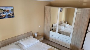 Un dormitori amb un llit, una tauleta de nit, un armari i un quadre a la paret.