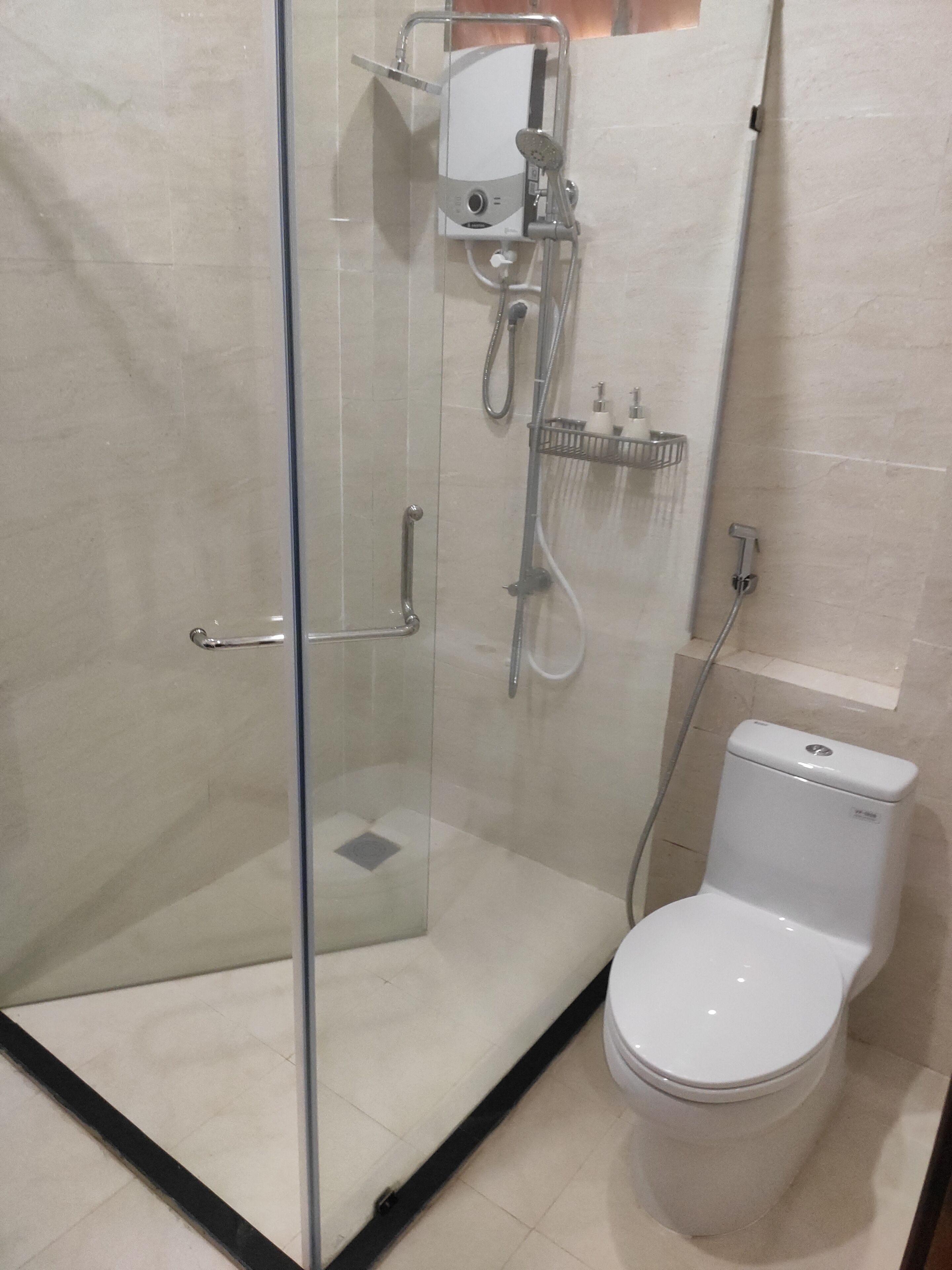 Un box de ducha con paredes de vidrio, equipado con un cabezal de ducha manual y un grifo monomando.