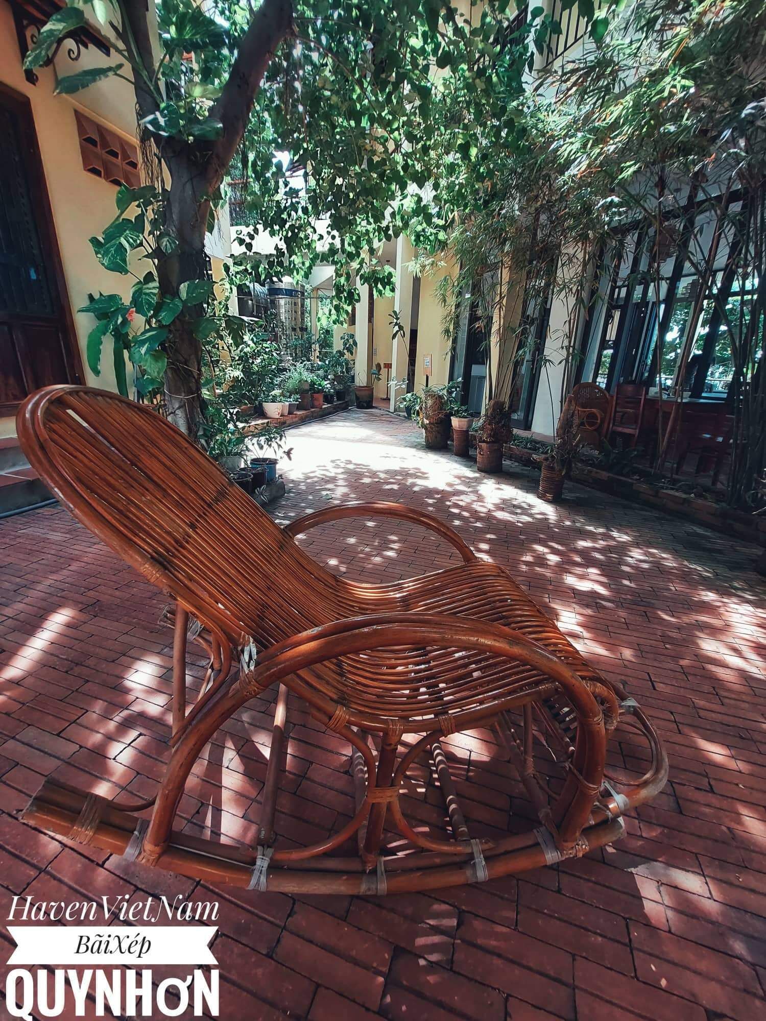 Un patio con sillas de mimbre, plantas en macetas y suelo de ladrillo.