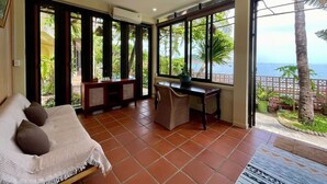 A room with a bed, a desk, and large windows offering a view of the sea. - Haven Boutique Hotel Quy Nhon (Quy Nhon Nam)