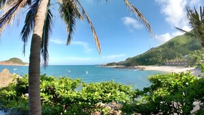 A beach with palm trees, clear blue sky, and calm sea. - Haven Boutique Hotel Quy Nhon (Quy Nhon Nam)