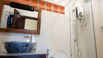 Un bany amb un mirall gran, un lavabo, un vàter i una dutxa amb portes de vidre.