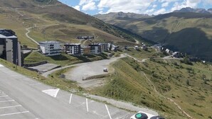 Un paysage montagneux avec une route menant à un ensemble de bâtiments modernes, qui pourraient être un hôtel ou un complexe touristique.
