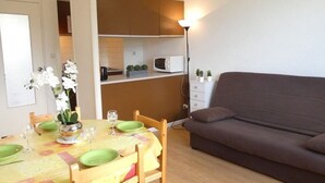 Un espace de vie compact comprenant un coin repas, une kitchenette et un canapé.