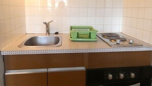 Une cuisine équipée d’un évier, d’une cuisinière et d’un égouttoir vert.