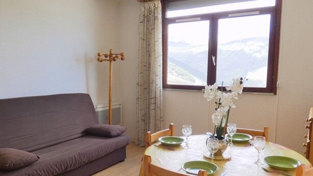 Une pièce comprenant un canapé, une table à manger, des chaises, une fenêtre avec vue et un porte-manteau.
