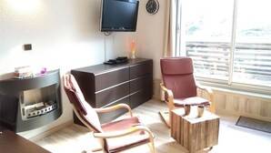 Un salon doté d’une cheminée, d’un téléviseur et d’une grande fenêtre donnant sur une terrasse en bois.