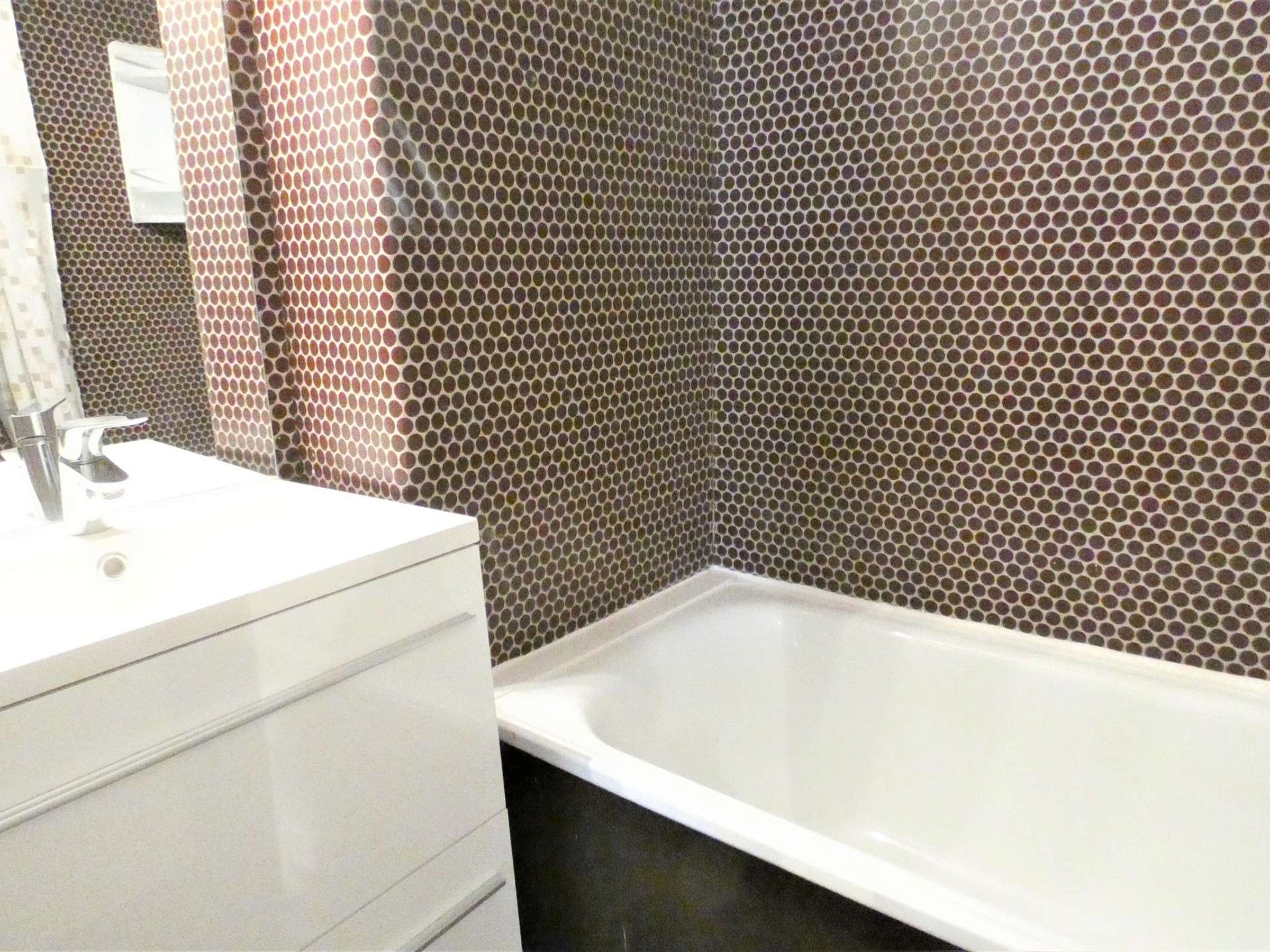A bathroom with a white sink, a mirror, and a bathtub.