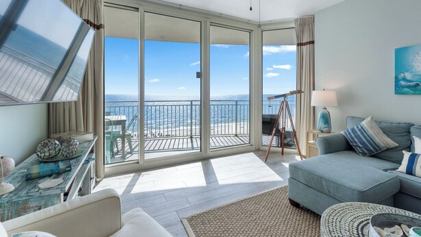 A spacious living room with a large sliding glass door leading to a balcony with a view of the ocean.