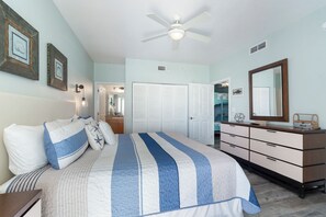 Ein Schlafzimmer mit Bett, Schminktisch und Deckenventilator.