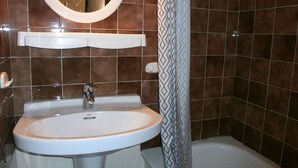 Ein Badezimmer mit weißem Waschbecken, einem Spiegel und einer Duschvorhang.