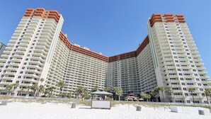 Korkea hotellirakennus, jossa on useita parvekkeita, ja joka sijaitsee lähellä hiekkarantaa.