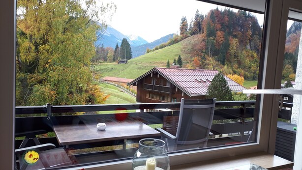 Ein Balkon mit Tisch, Stuhl und einer Vase mit Sonnenblumen.