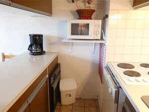 Une cuisine compacte équipée d’un four à micro-ondes, d’une machine à café et d’une petite poubelle.