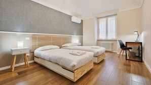 Une chambre avec deux lits, un bureau, une chaise, un radiateur et une fenêtre.