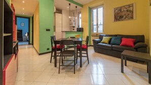 Una sala de estar con un sofá, una mesa de comedor con sillas y una zona de cocina.