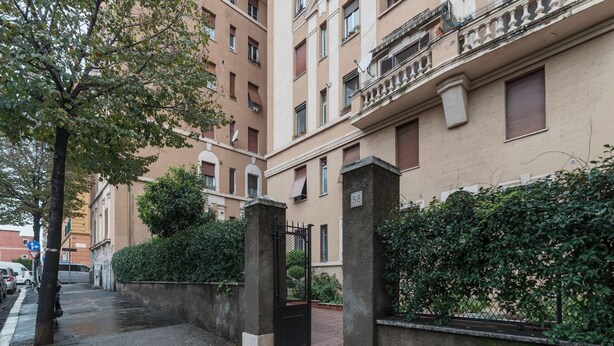 Un edificio residencial con entrada porticada, el número 58 a la vista y un árbol en el lado izquierdo.