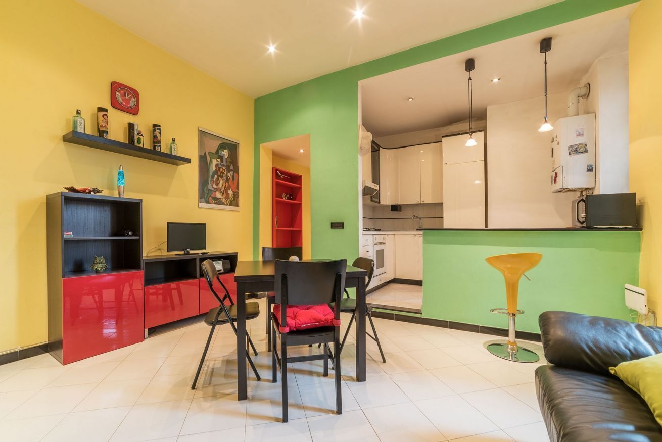 A modern living room with a dining area, kitchen, and a red and black chair.